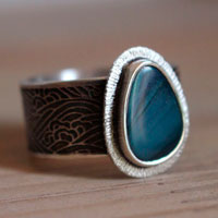 Under the lights of the pole, boreal waves ring in sterling silver and boulder opal