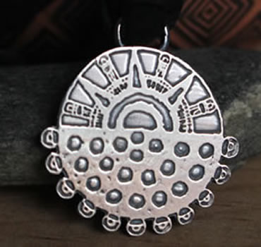 Eclipse necklace that takes up the Aztec motif of the sun and the night